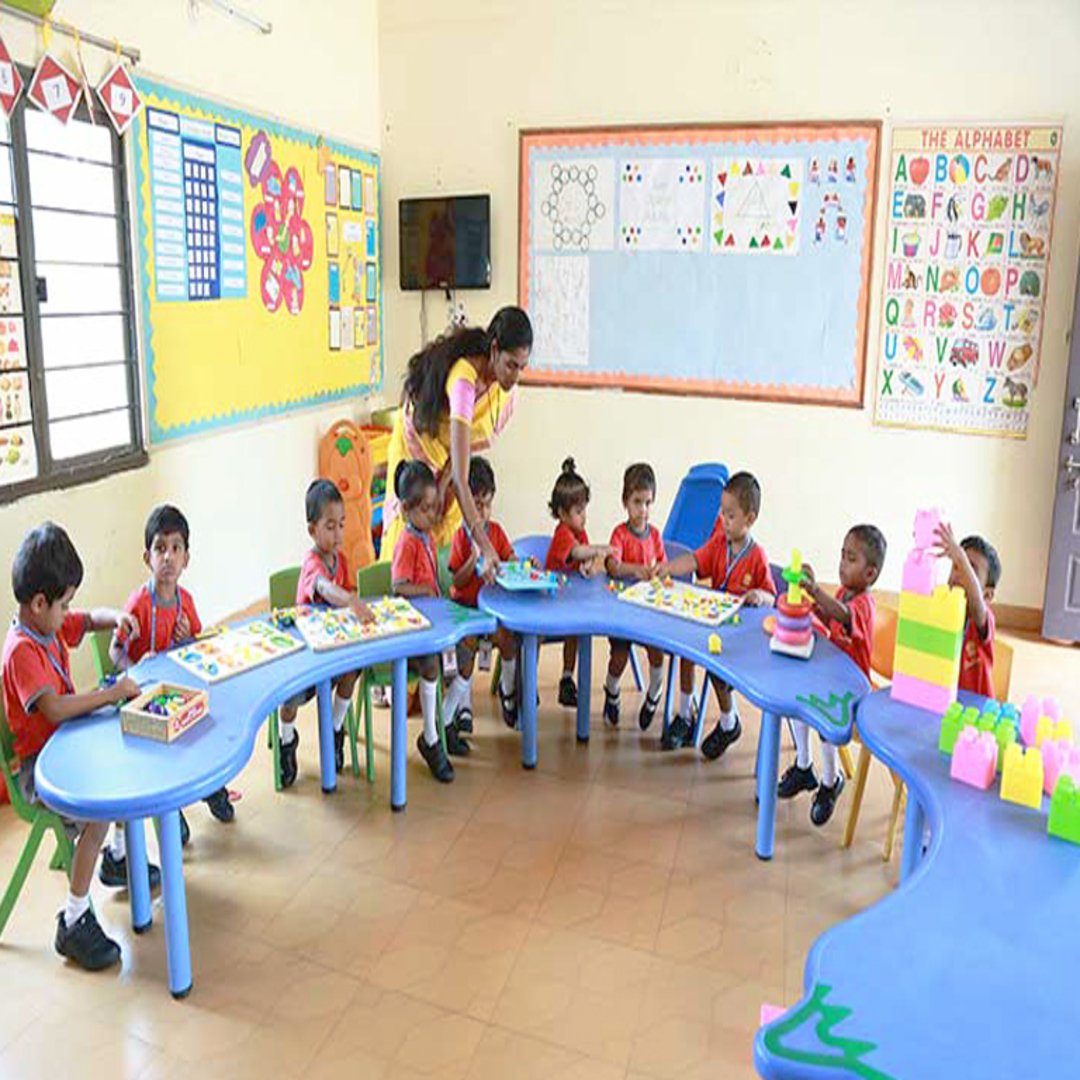 Portrait of female English teacher holding open book, smiling in classroom with students in background